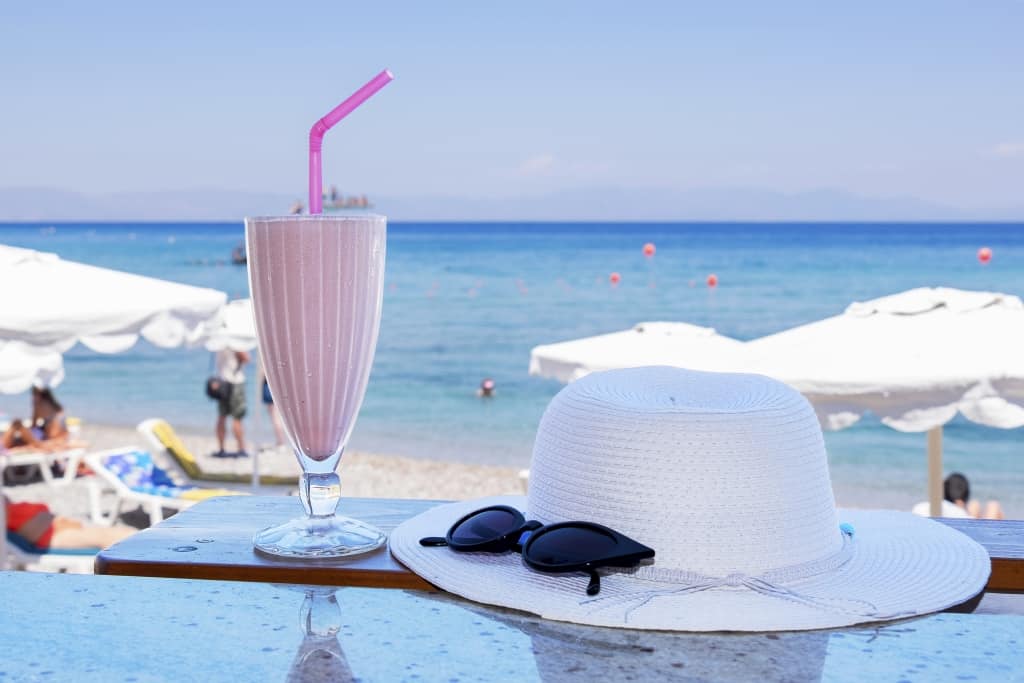 Milkshake, hoed en zonnebril aan het strand