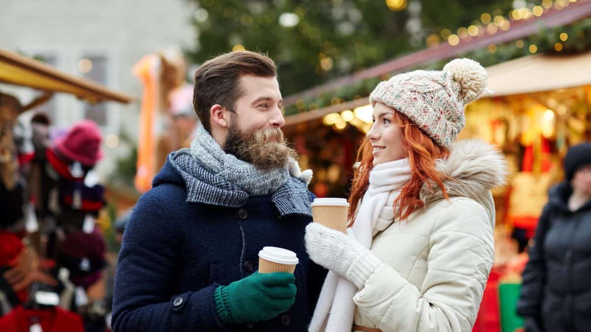 Man en vrouw met warm drinken op een kerstmarkt