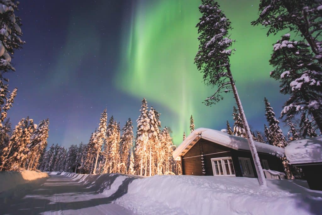 Noorderlicht boven een boshuisje in Lapland
