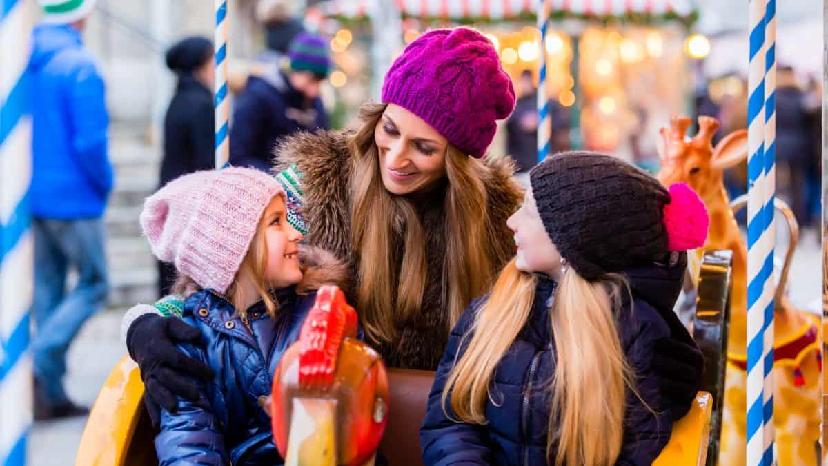 Vrouw met kinderen in een draaimolen op de kerstmarkt