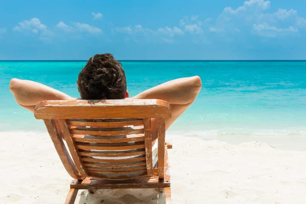 Man in een strandstoel aan het relaxen op het strand