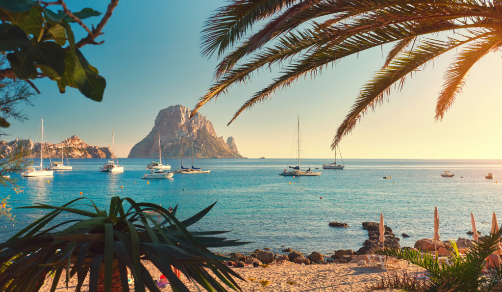 Strand van Cala d’Hort op Ibiza met zeilboten op zee en uitzicht op Es Vedra
