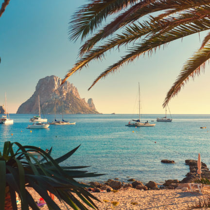 Strand van Cala d’Hort op Ibiza met zeilboten op zee en uitzicht op Es Vedra