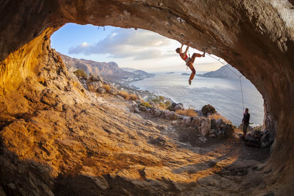 Jonge vrouw aan het rotsklimmen in een grot op Kalymnos, Griekenland