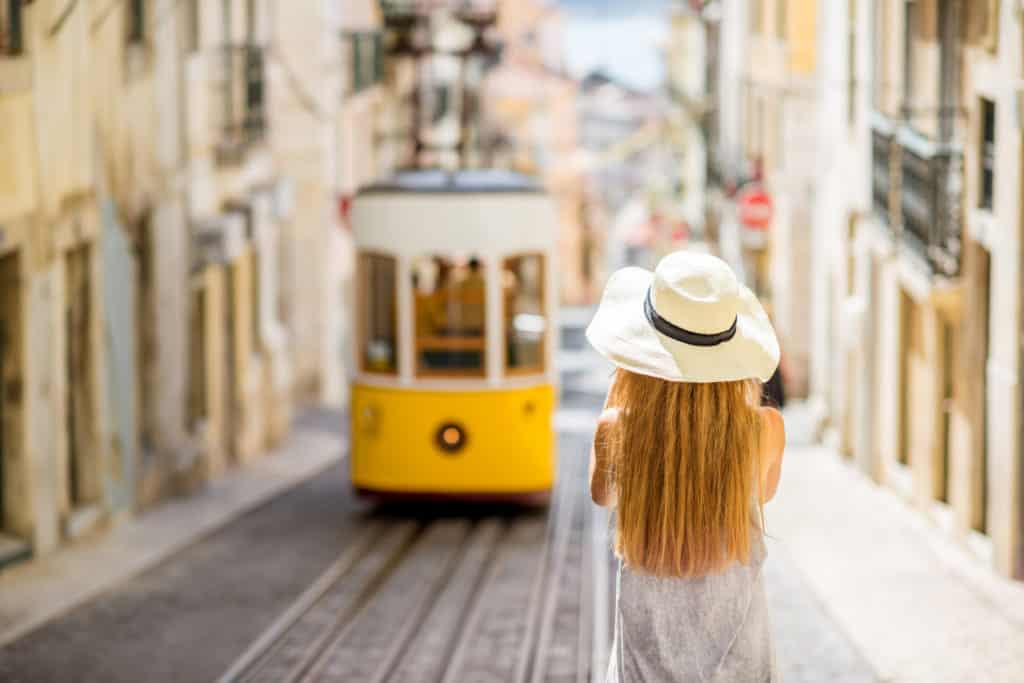 vrouw met hoed kijkt naar bekende gele tram lissabon portugal