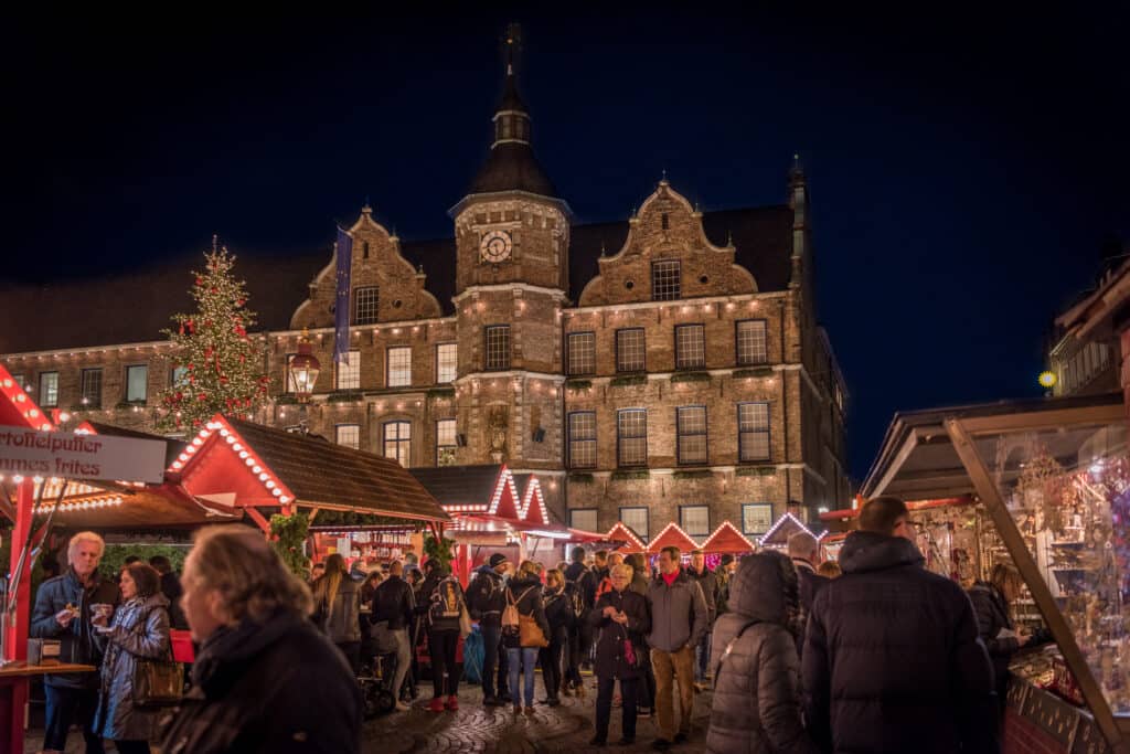 Verlichte kerstmarkt op beroemde Burgplatz met uitzicht op oude herenhuis in Düsseldorf, Duitsland