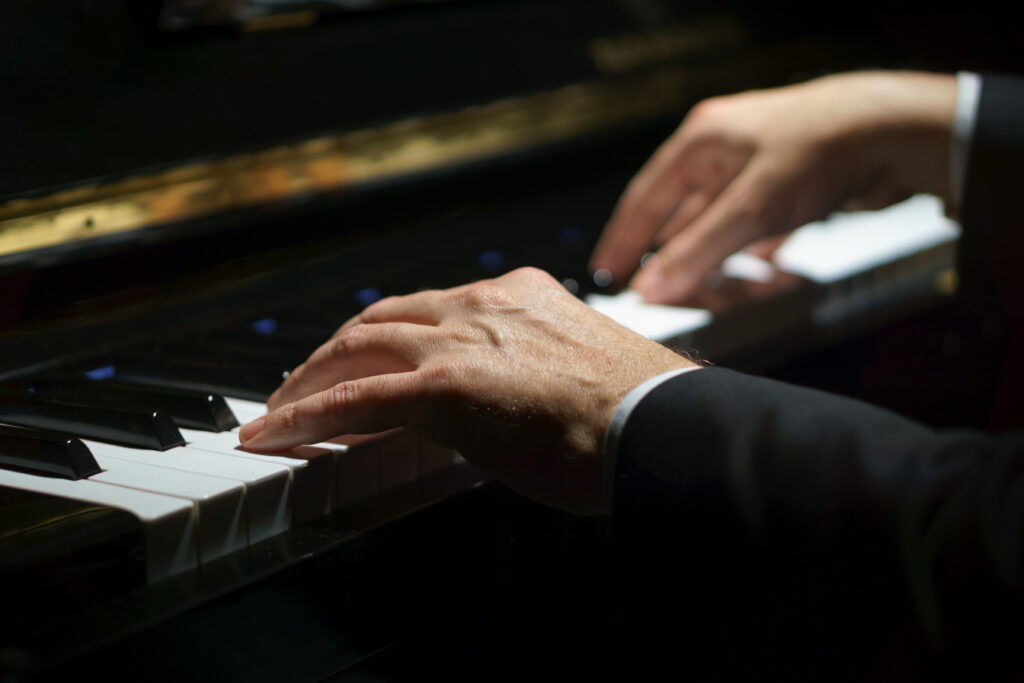 Detail van een pianospeler met twee handen op een piano