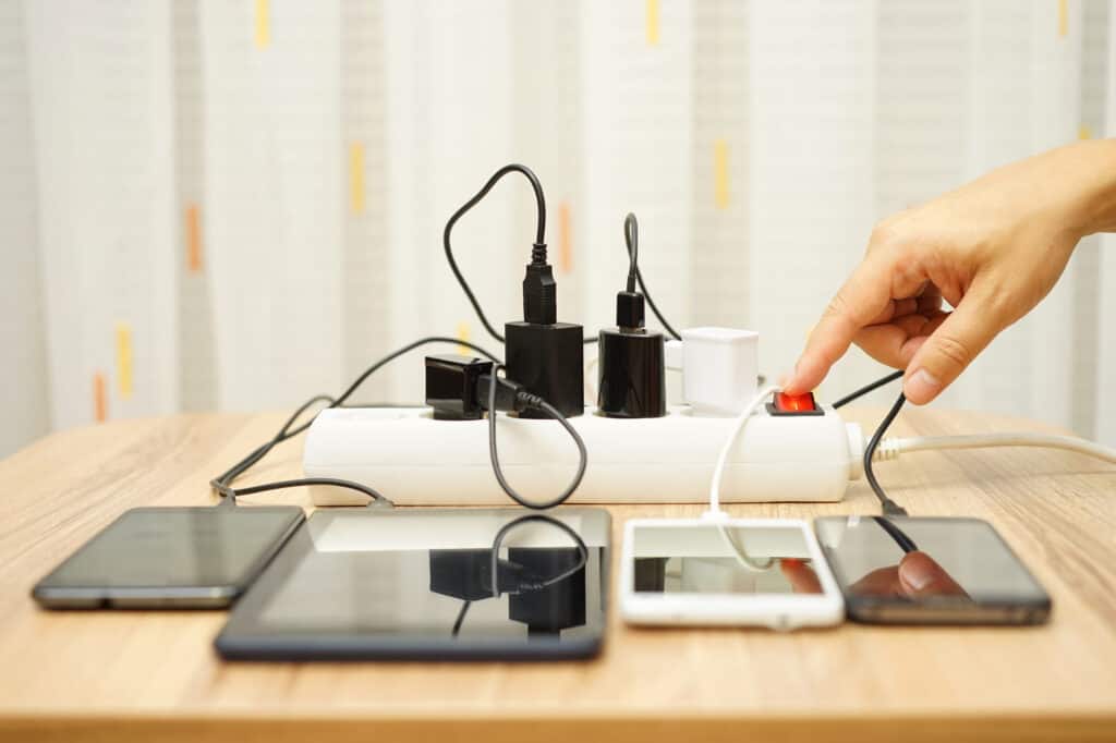 Man drukt een stekkerdoos aan met veel aangesloten elektronica
