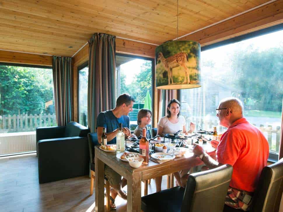 Familie is gezellig samen aan het eten in een huisje van Vakantiepark Dierenbos