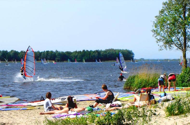 Mensen op het strand en windsurfers op het Veluwemeer