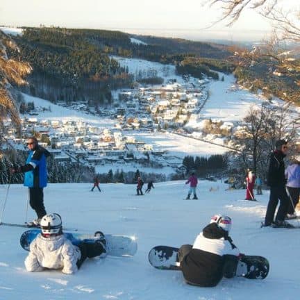 Snowboarders en skiërs op de piste met uitzicht op Willingen, Duitsland