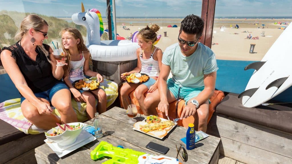 Familie aan het eten in een strandtent bij zee