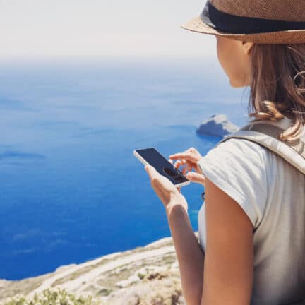 Vrouw met telefoon bij een klif met uitzicht op zee