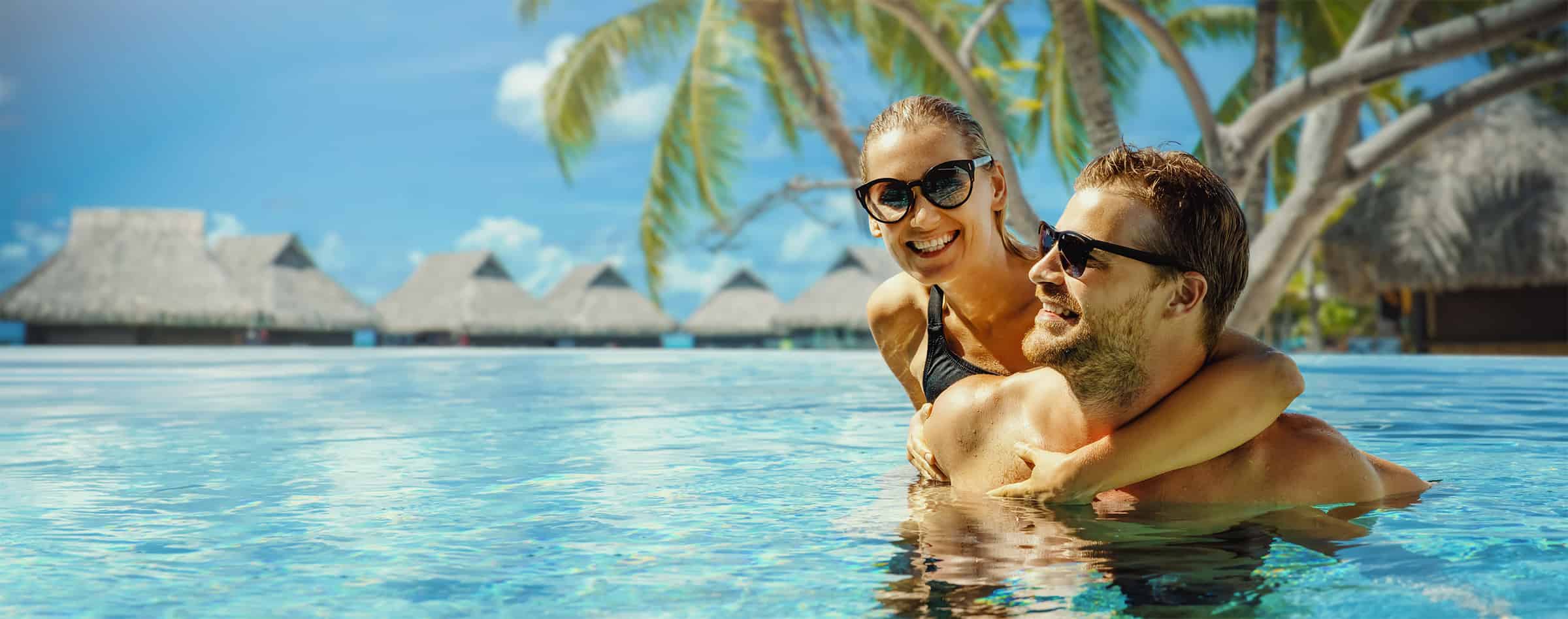 Man en vrouw in zwembad met palmbomen op de achtergrond